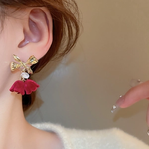 Close-up of red velvet petal earrings with gold bow and crystal on a model's ear