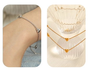 Detailed view of silver and gold heart pendant bracelets worn and on a glass
