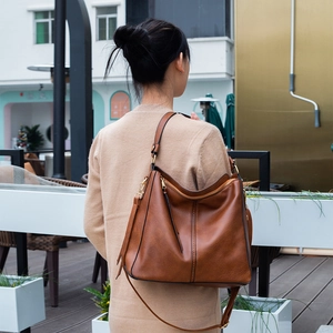 Brown retro large capacity shoulder bag shown on model in an outdoor cafe setting