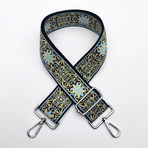 Close-up of thick ethnic jacquard strap with blue gold embroidery and silver metal clasps