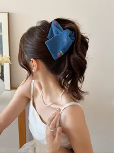 Gros plan d'un chouchou en denim bleu avec broderie cerise porté en queue de cheval