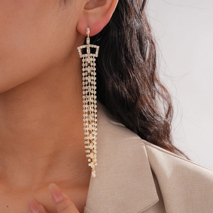 Macro view of gold long tassel earrings with sparkling crystals worn by a model