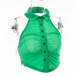 Dettaglio del top verde con allacciatura al collo, colletto a revers e bottoni anteriori