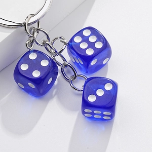 Detail of three transparent blue dice keychains with polished silver metal chain and ring