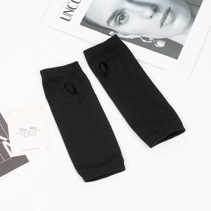 Detail of black knitted arm sleeves with thumb holes on white background decor