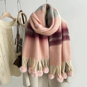 Close-up of rainbow mohair scarf featuring soft pink pom-poms and gradient knit texture