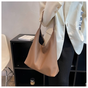 Detail of caramel lychee grain leather tote bag worn by a model in a beige suit