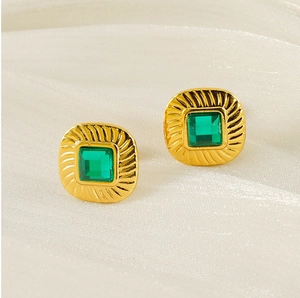 Close-up of vintage square gold earrings with emerald zircon and spiral texture detail