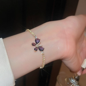 Gros plan d'un élégant bracelet papillon doré avec pierres violettes sur un poignet