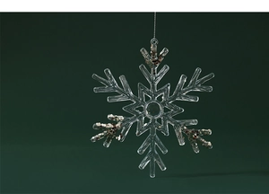 Close-up of a clear acrylic snowflake ornament with gold glitter flakes on dark green background