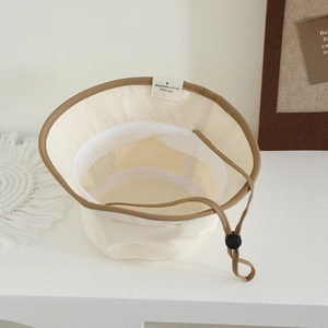 Detail of baby sun hat with brown piping, adjustable windproof drawstring and cute inner tag