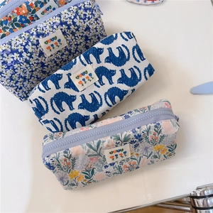 Close-up of three floral canvas stationery pouches with zippers and flower labels