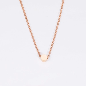 Primo piano di una collana minimalista in oro rosa con ciondolo a perla tonda lucida su bianco