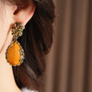 Macro shot of vintage baroque drop earrings with orange teardrop stone and colorful gems