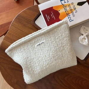 Minimalist beige wool tweed makeup bag with 'simple wish' label on a wooden desk