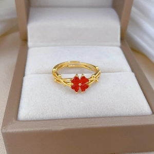Détail d'une bague dorée avec trèfle à cœurs rouges sur un écrin à bijoux en soie douce