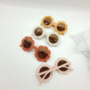 Close-up of four flower-shaped kids sunglasses in cream, yellow, orange and pink tones
