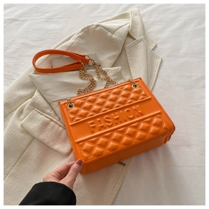 Detail of orange quilted PU leather bag with embossed fashion lettering and chain strap