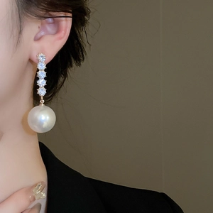 Detail of drop earring featuring vertical crystals and a large white pearl drop
