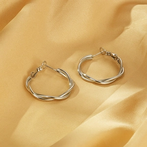 Detail shot of silver twisted hoop earrings on an elegant golden silk fabric background