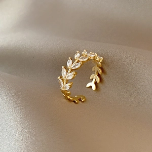 Golden laurel leaf open ring with marquise-cut zircons on elegant beige silk fabric