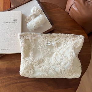 Vue détaillée d'une trousse à maquillage en dentelle blanche avec nœud et chouchou