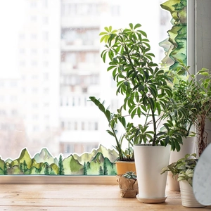 Detail of forest mountain wall stickers applied to a window sill with potted plants