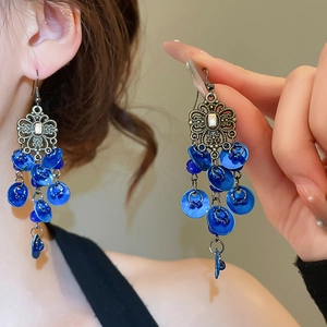 Close-up of vintage ethnic earrings with blue shell fringe and intricate metal carving