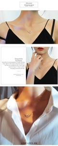Detail of a rose gold angel wing necklace with a dancing stone on a female model