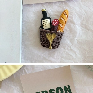 Detailed view of 3D food basket fridge magnet with baguette and wine on paper background