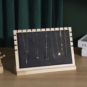 Solid wood necklace display stand with black leather panel and five gold jewelry pendants