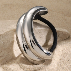 Minimalist silver stainless steel hair tie with a polished metal sleeve on sand and stones