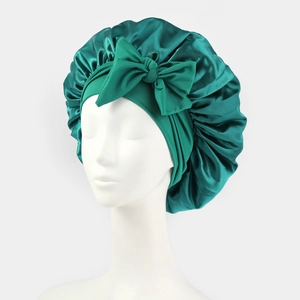 Detailed view of the green satin sleep bonnet with a decorative bow and elastic band