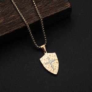 Detailed view of golden shield pendant with silver cross and rustic bark texture