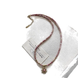Stainless steel necklace with purple gradient beads and a gold sun pendant on white base