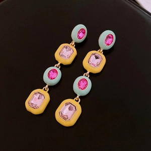 Detail of drop earrings with mint green and lemon yellow crystals on a black background