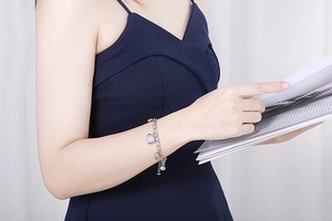 Gros plan d'un bracelet double chaîne argentée avec pendentifs cœur sur un mannequin