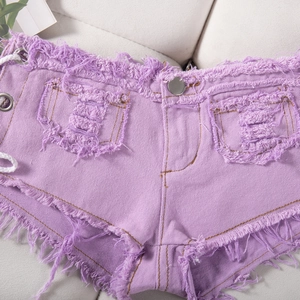 Dettaglio ravvicinato di pantaloncini denim viola chiaro con bordi sfrangiati e lacci