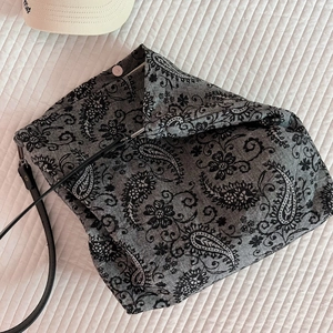 Detail view of grey cotton tote bag with black paisley patterns and magnetic silver buckle
