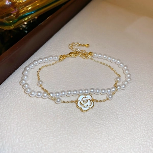 Détails d'un bracelet double rang doré avec camélia blanc et perles d'imitation