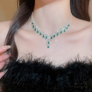 Detail of luxury necklace featuring green teardrop gemstones and sparkling crystals on model