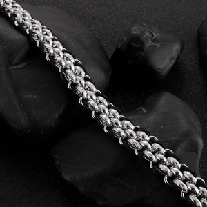 Macro shot of men's leather cord bracelet featuring silver wolf heads on black stones