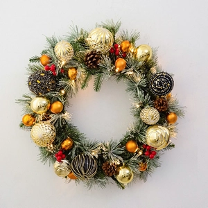 Christmas wreath with green pine needles, golden ornaments, pine cones and warm LED lights