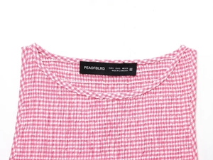 Gros plan sur la texture du tissu vichy rose et blanc et l'étiquette de la marque