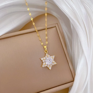 Detail view of gold snowflake necklace with sparkling zircon pendant on silk background