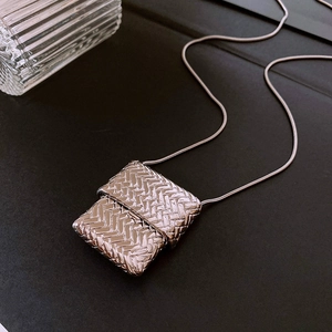 Detailed macro view of silver square woven pendant on a smooth metal snake chain necklace