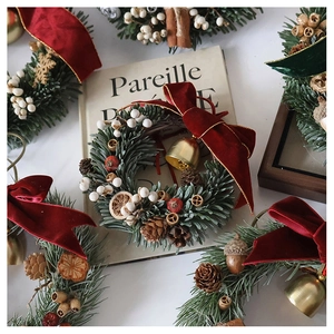 Detail of Christmas wreath with pine needles, red velvet bow, pinecones and gold bells
