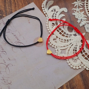 Detail of red and black heart charm braided rope bracelets with adjustable knots