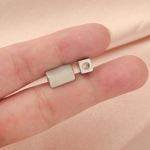 Brushed silver square metal spacer beads for DIY jewelry held on fingers for scale