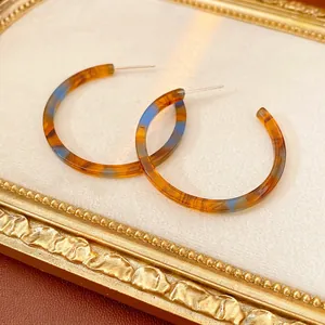 Orecchini a cerchio a C in resina marmorizzata ambra e blu in una cornice dorata